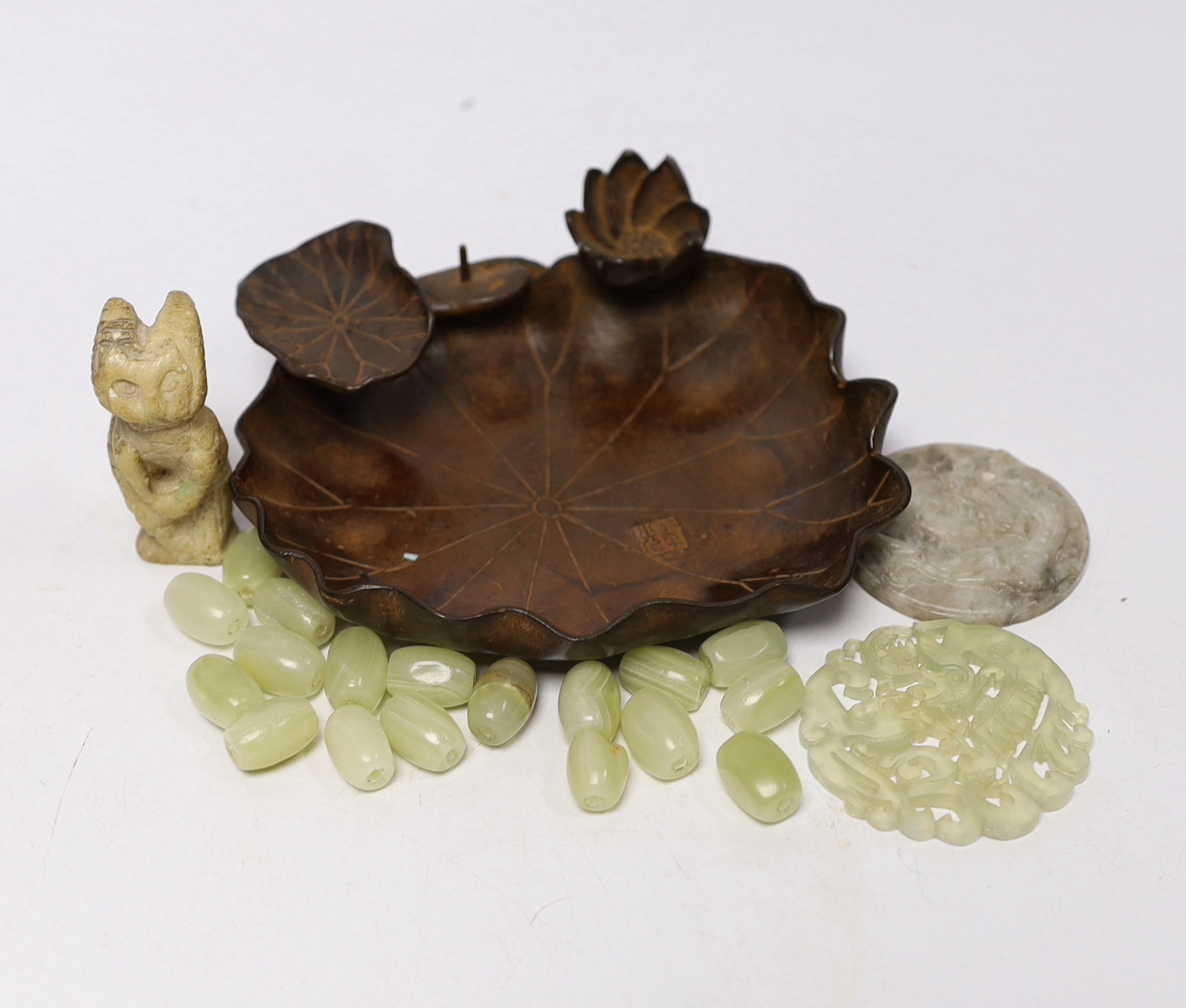 A collection of Chinese items including a bronze tray in the form of a water lily, two bowenite or jadeite discs, a soapstone cat and a bag of hardstone beads, bronze 14cm diameter